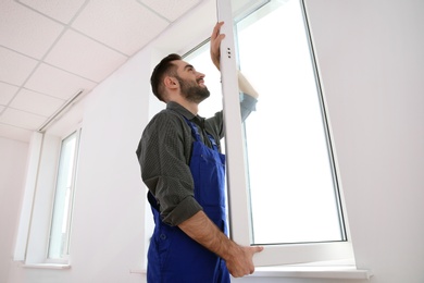 Photo of Construction worker installing plastic window in house