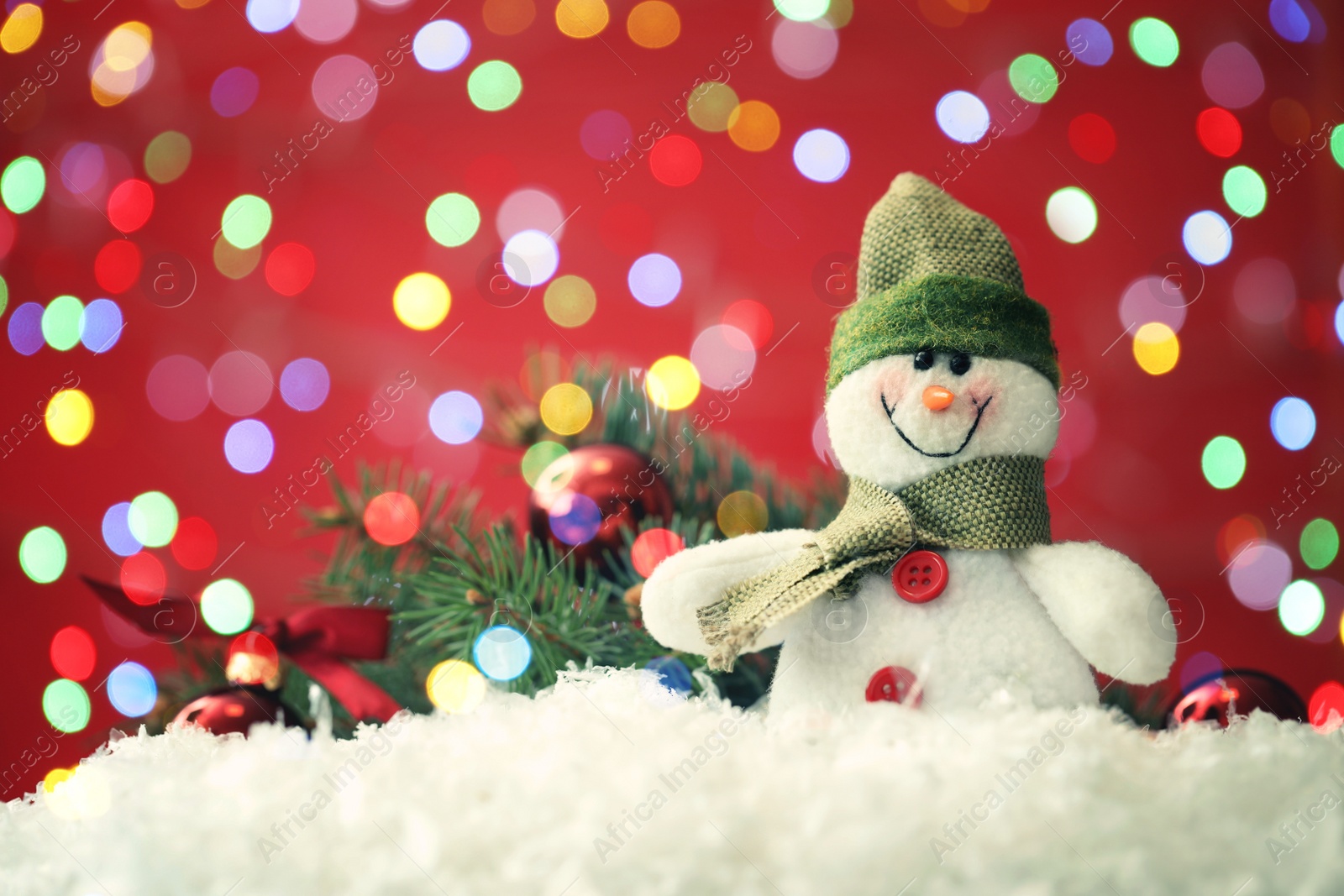 Image of Cute snowman and fir tree branches with Christmas balls on snow against red background. Space for text