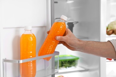 Man taking bottle of juice out of refrigerator, closeup