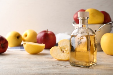 Photo of Composition with bottle of apple vinegar on table. Space for text