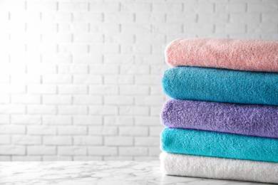 Photo of Stack of clean bath towels on white marble table. Space for text