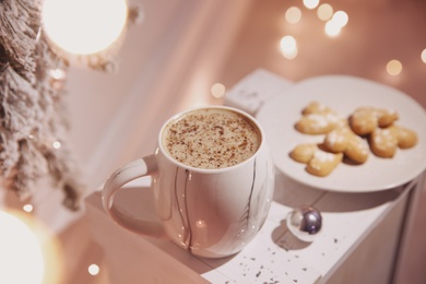 Photo of Cup of tasty hot drink and cookies indoors. Christmas atmosphere