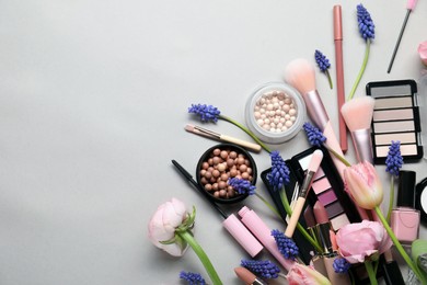 Photo of Flat lay composition with different makeup products and beautiful spring flowers on gray background, space for text