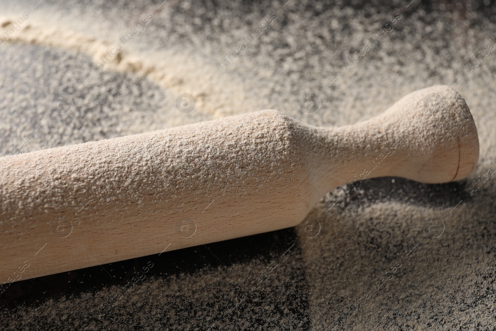 Photo of Scattered flour and rolling pin on table, closeup