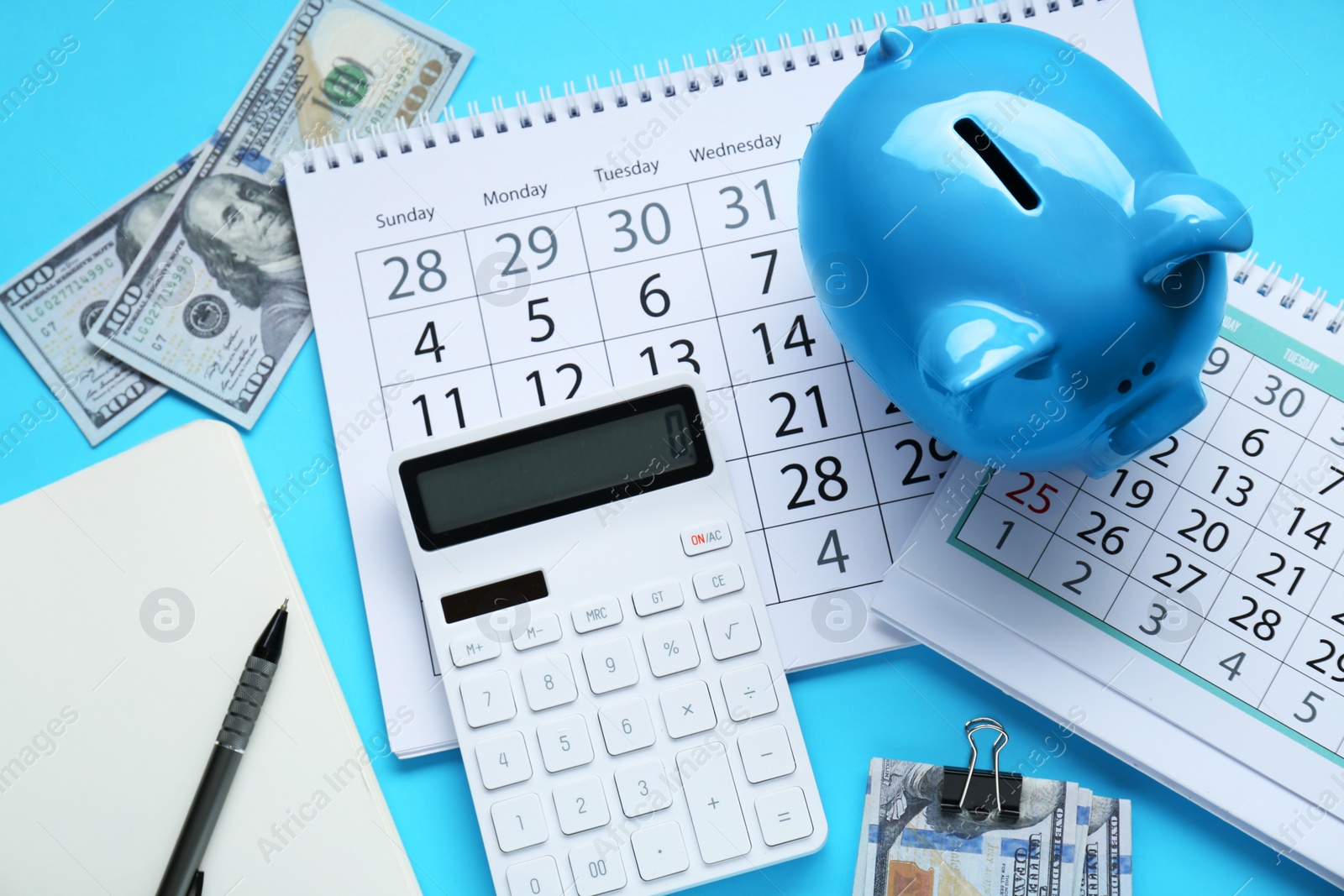 Photo of Flat lay composition with piggy bank and calculator on light blue background
