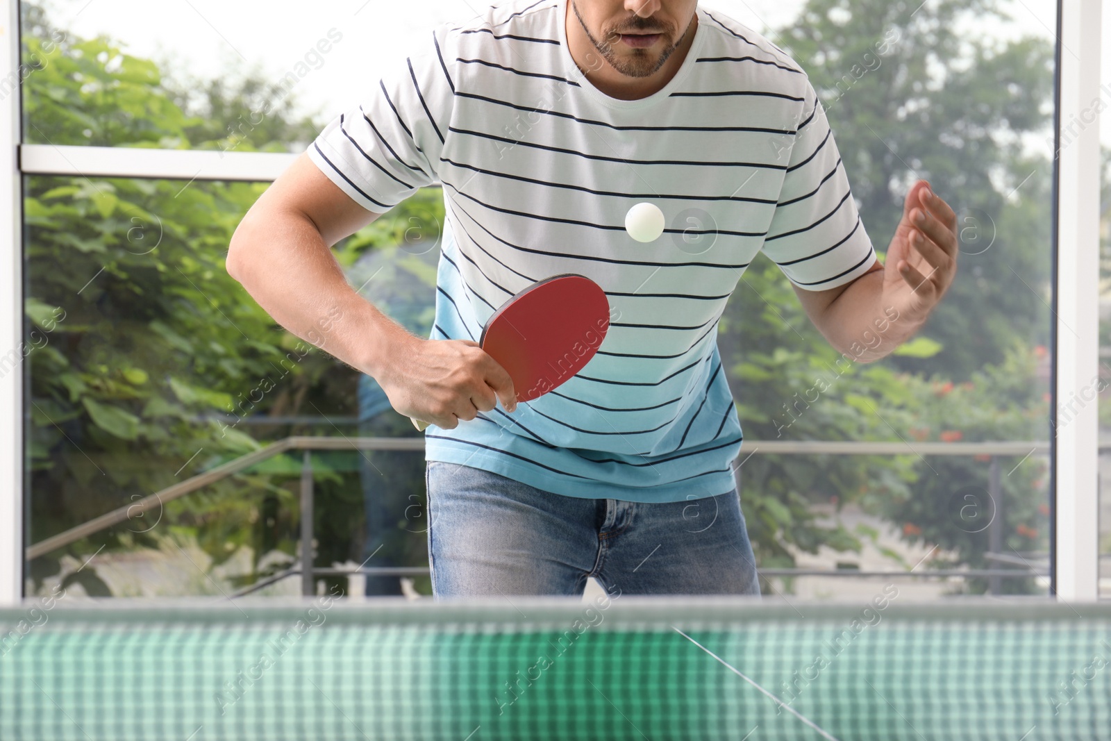 Photo of Man playing ping pong indoors, closeup view