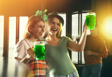 Photo of Young women with glasses of green beer in pub. St. Patrick's Day celebration