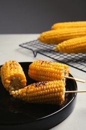 Ceramic plate with grilled corn cobs on light table