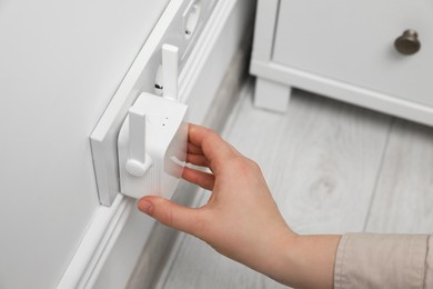 Photo of Woman turning on wireless Wi-Fi repeater indoors, closeup