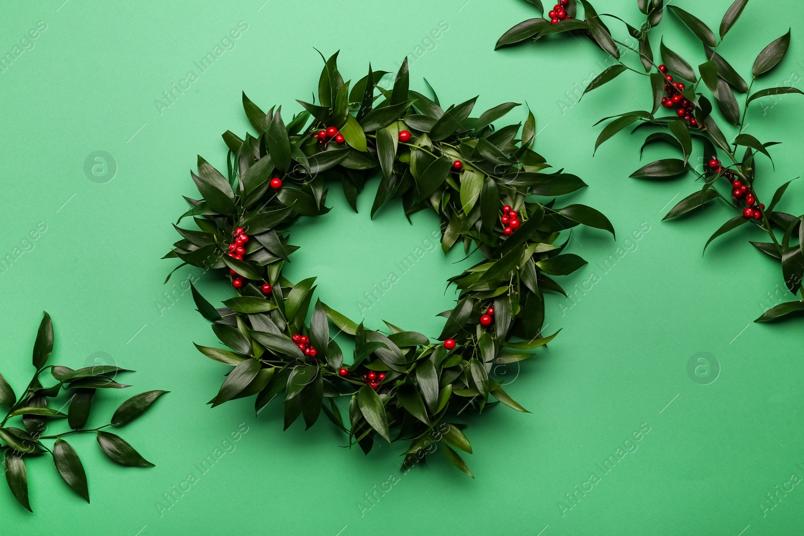 Photo of Beautiful handmade mistletoe wreath on green background, flat lay. Traditional Christmas decor