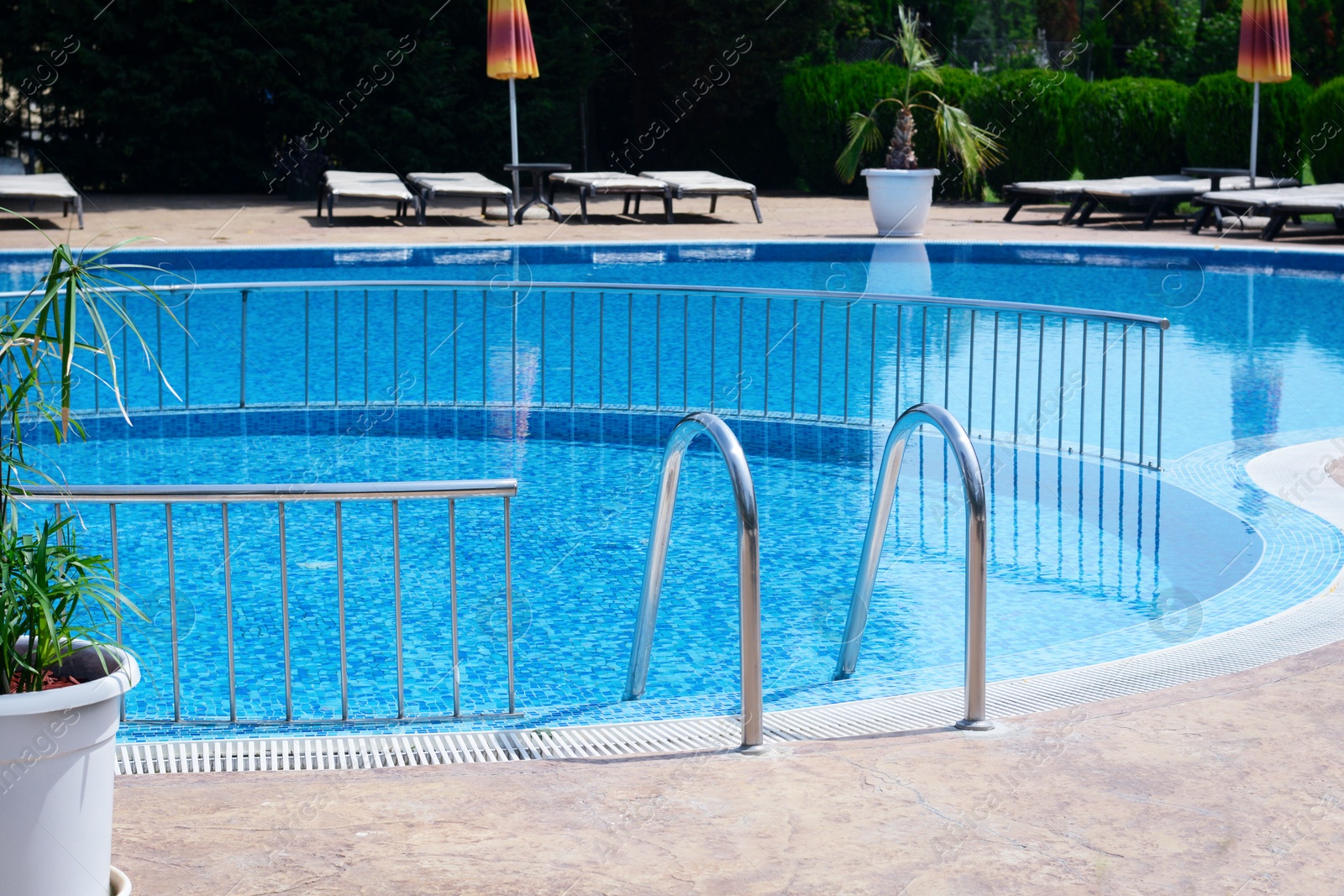 Photo of Outdoor swimming pool with ladder and railing on sunny day