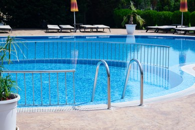 Photo of Outdoor swimming pool with ladder and railing on sunny day