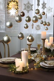 Photo of Christmas table setting with burning candles and festive decor