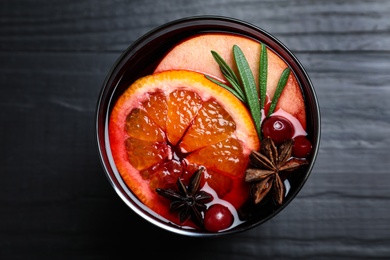 Photo of Cup of tasty mulled wine on black wooden table, top view