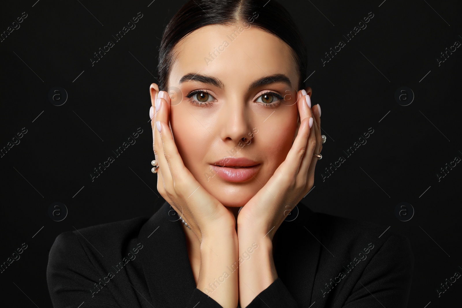 Photo of Young woman wearing elegant pearl rings on black background