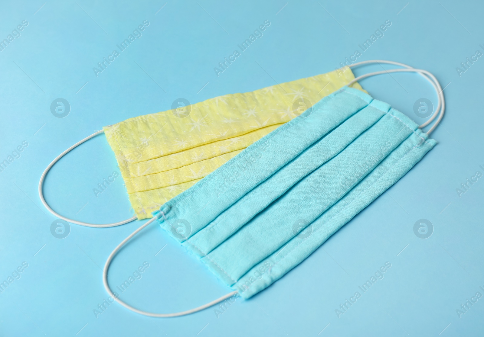 Photo of Homemade protective face masks on light blue background