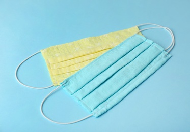 Photo of Homemade protective face masks on light blue background