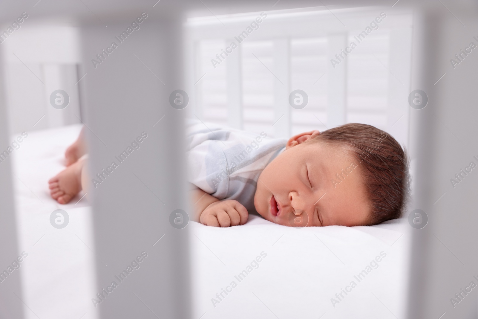 Photo of Cute newborn baby sleeping in crib. Bedtime