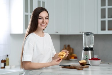 Photo of Beautiful young woman preparing mango for tasty smoothie at white marble table in kitchen