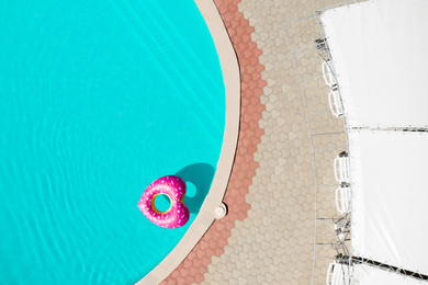 Image of Heart shaped inflatable ring floating in swimming pool, top view. Summer vacation