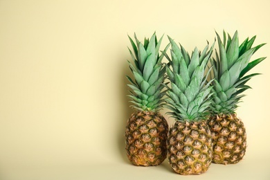 Photo of Ripe juicy pineapples on light yellow background. Space for text