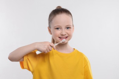 Photo of Happy girl brushing her teeth with electric toothbrush on white background
