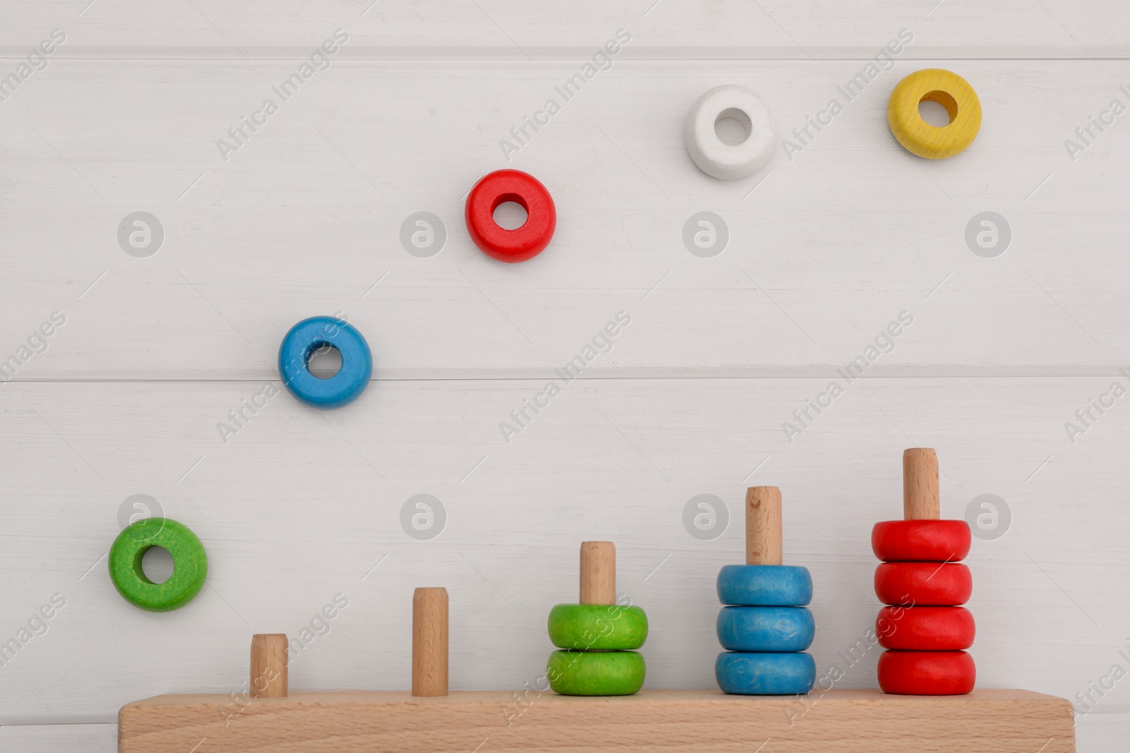 Photo of Motor skills development. Stacking and counting game pieces on white wooden table, flat lay
