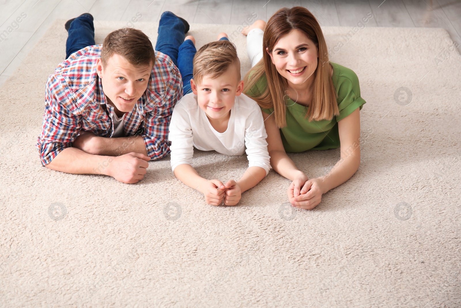 Photo of Happy family lying on cozy carpet at home