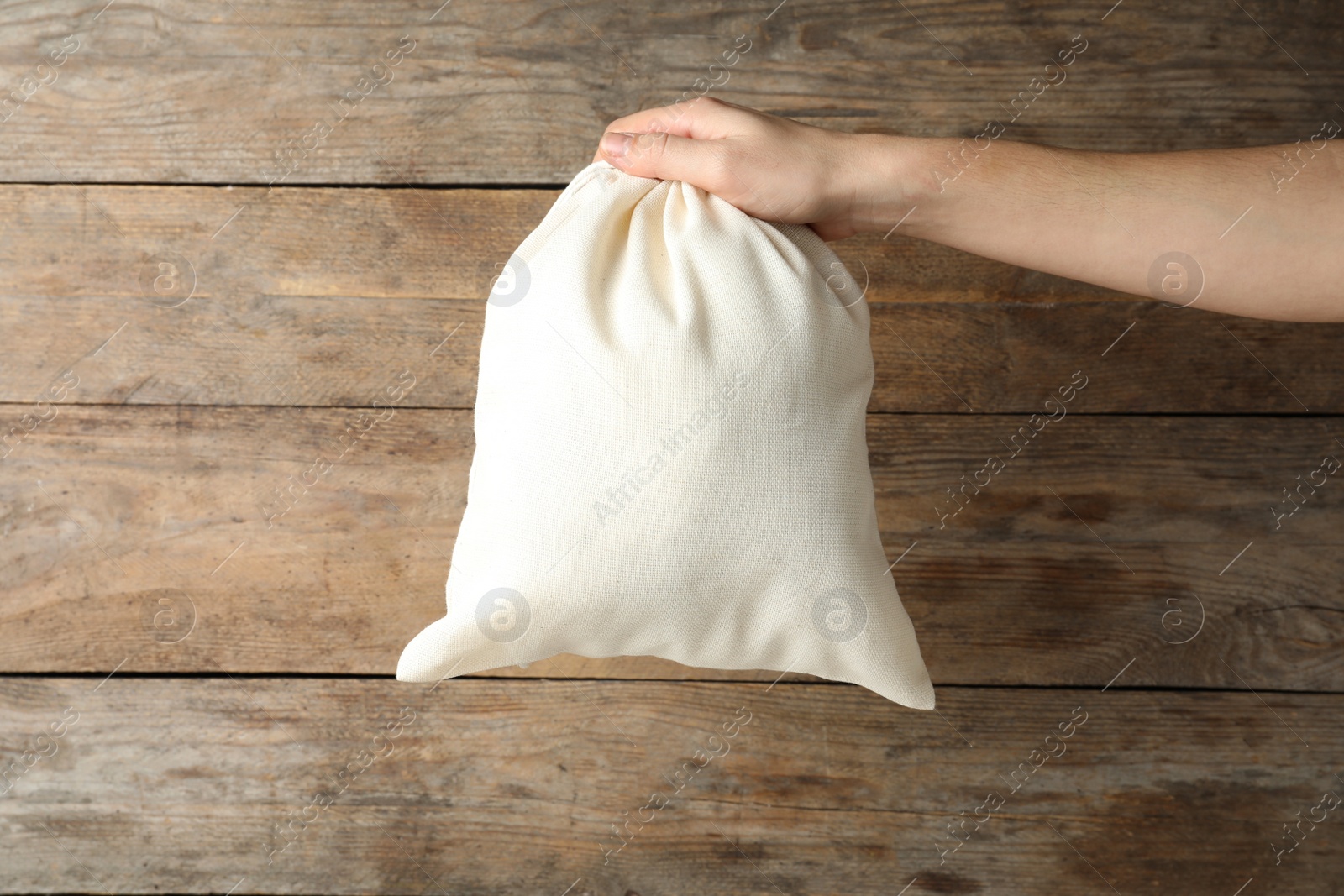 Photo of Woman holding full cotton eco bag on wooden background, closeup