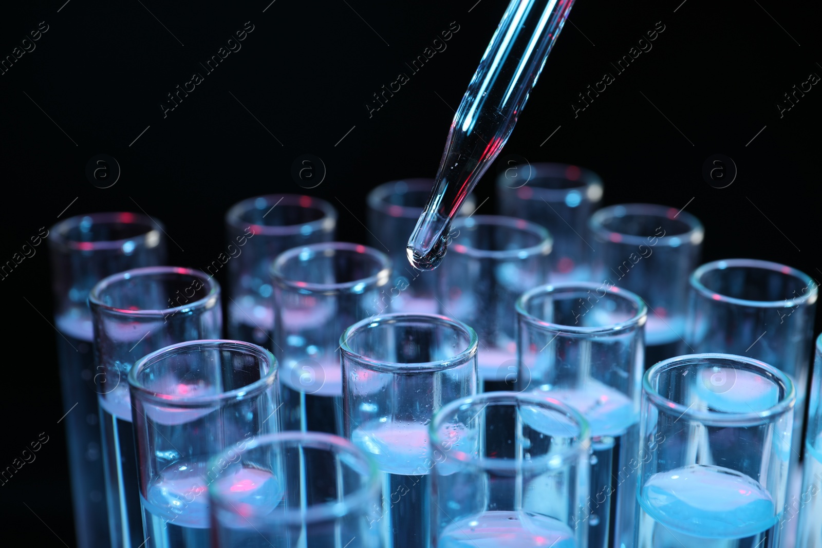 Photo of Dripping reagent into test tube on black background, closeup. Laboratory analysis