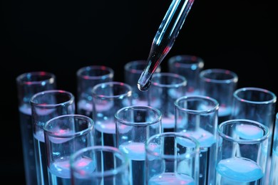 Photo of Dripping reagent into test tube on black background, closeup. Laboratory analysis