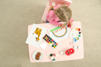 Photo of Cute little child painting at table, top view