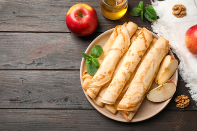 Delicious thin pancakes on wooden table, flat lay. Space for text