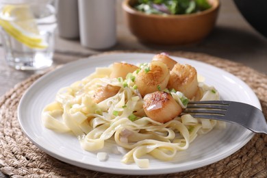 Photo of Delicious scallop pasta with onion served on table, closeup