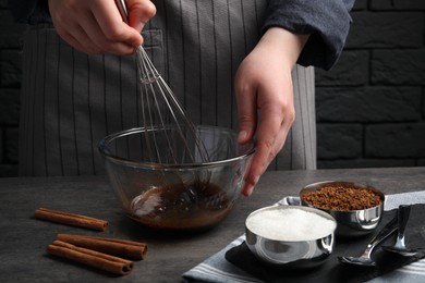 Woman whipping cream for dalgona coffee at grey table, closeup