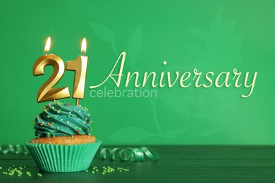 Coming of age party - 21th birthday. Delicious cupcake with number shaped candles on green wooden table. Anniversary celebration