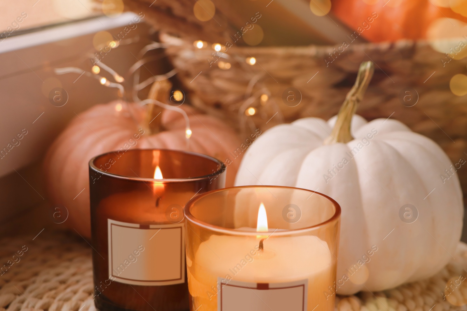 Photo of Scented candles and pumpkins on window sill indoors