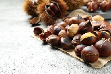 Photo of Delicious roasted edible chestnuts on grey table, closeup
