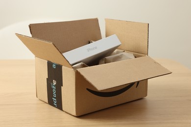 Leiden, Netherlands - October 6, 2023: New iPhone 15 Pro Max and crumpled paper in cardboard box on wooden table. Amazon delivery