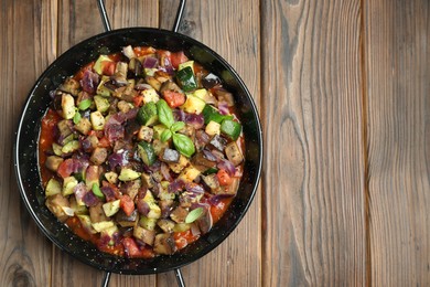 Photo of Delicious ratatouille in baking dish on wooden table, top view. Space for text