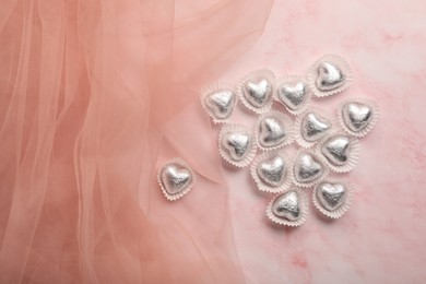 Delicious heart shaped chocolate candies on pink background, top view. Space for text