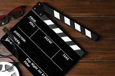 Photo of Clapperboard, film reel and 3D glasses on wooden table, flat lay