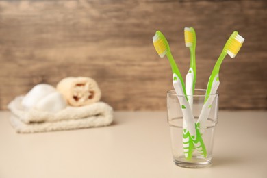 Toothbrushes in glass on beige table. Space for text