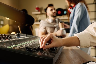 Photo of Woman working with professional mixing console in modern radio studio, closeup