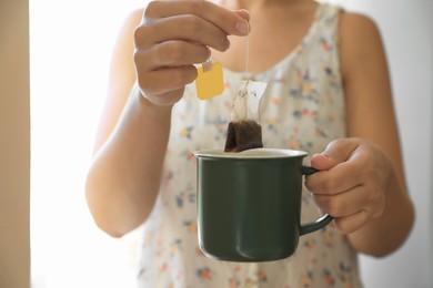 Photo of Woman taking tea bag out of cup, closeup
