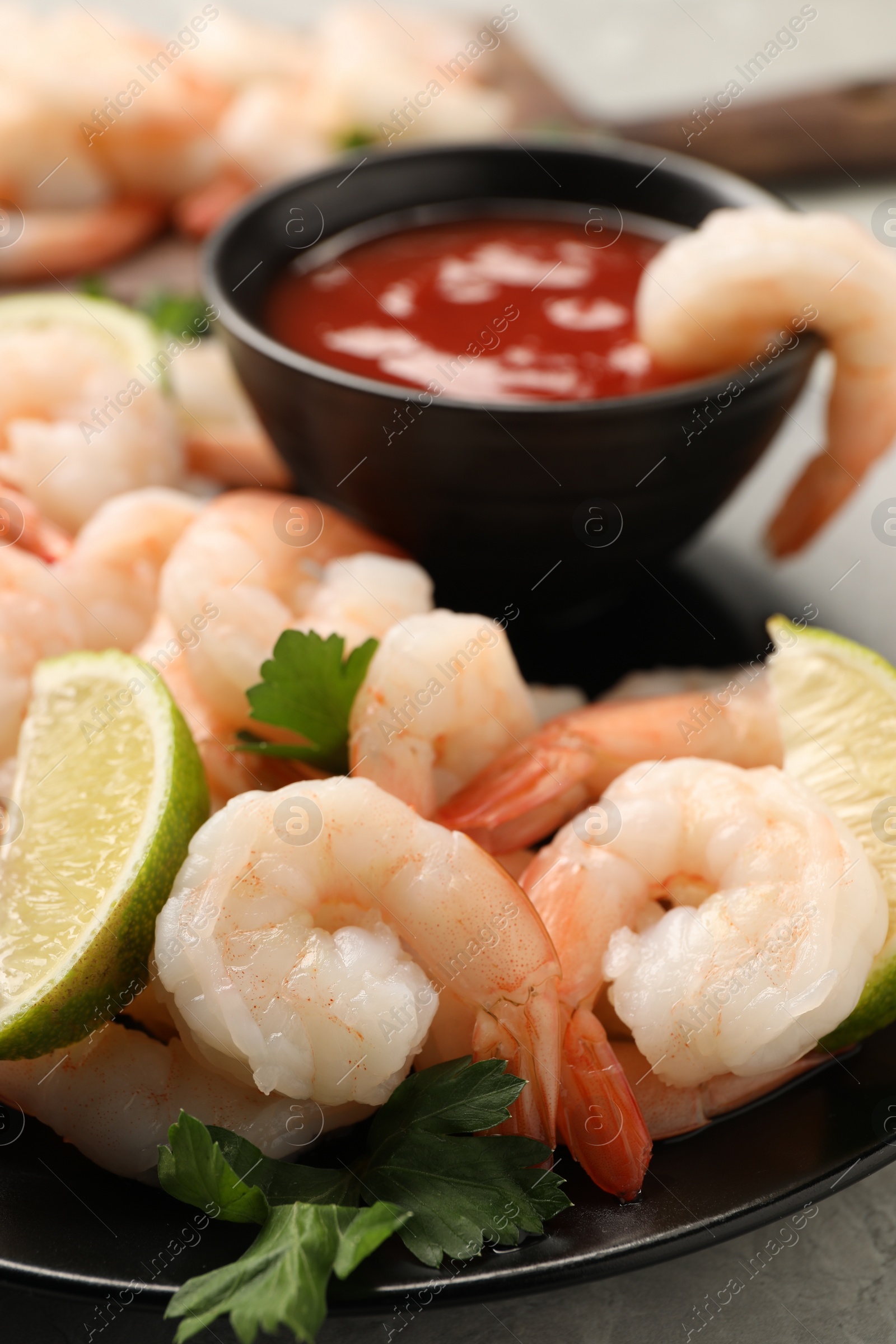 Photo of Tasty boiled shrimps with cocktail sauce, parsley and lime on table, closeup