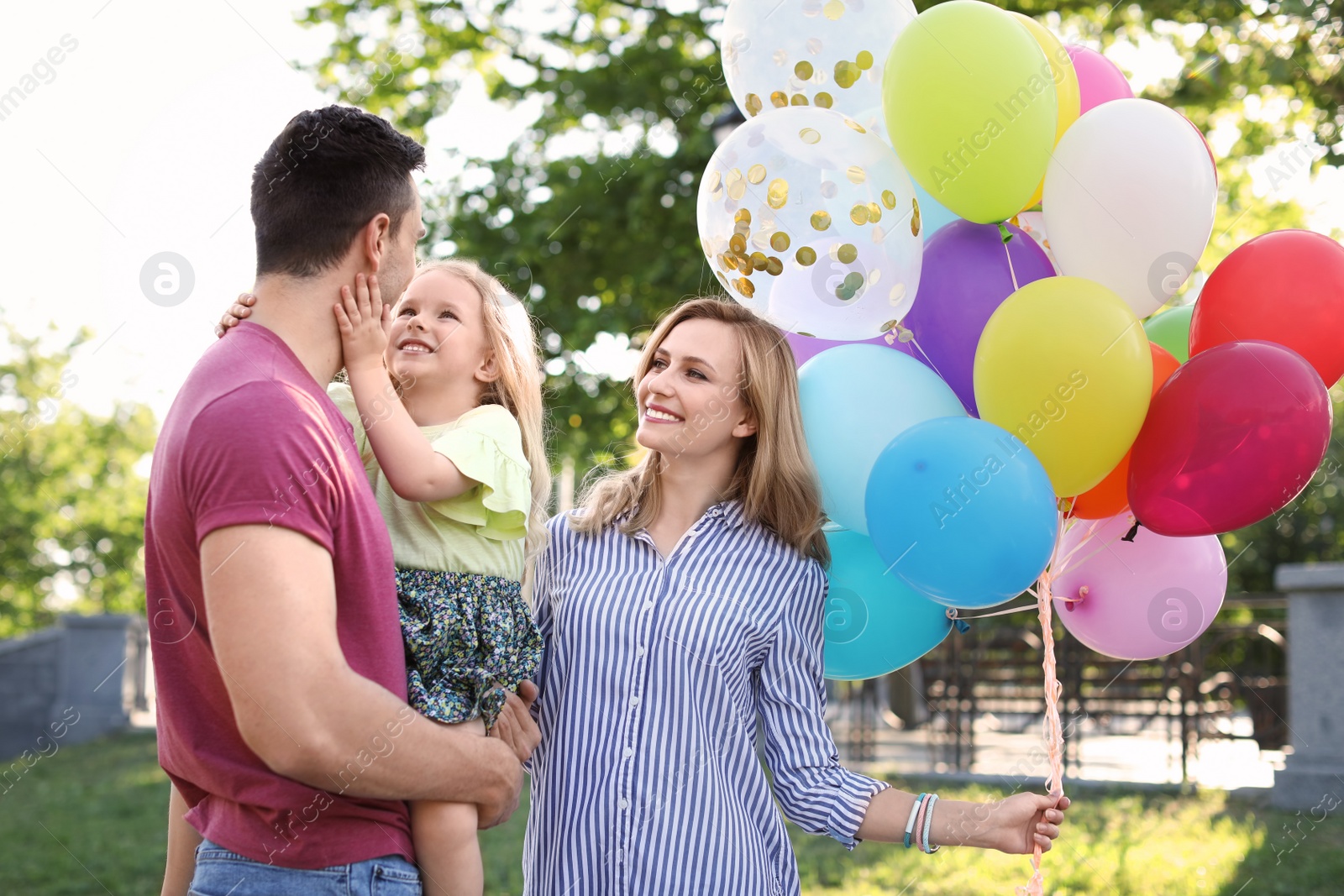 Photo of Happy family with colorful balloons outdoors on sunny day