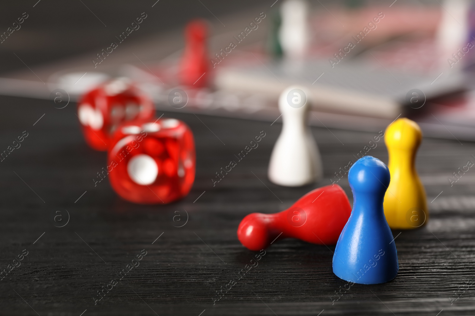 Photo of Pawns and dices on dark wooden table, closeup. Board game