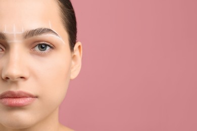 Photo of Eyebrow correction. Young woman with markings on face against pink background, closeup. Space for text