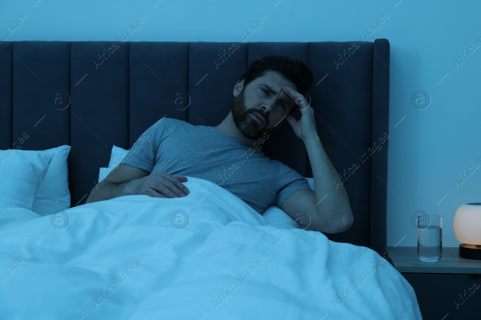 Photo of Man suffering from headache in bed at night